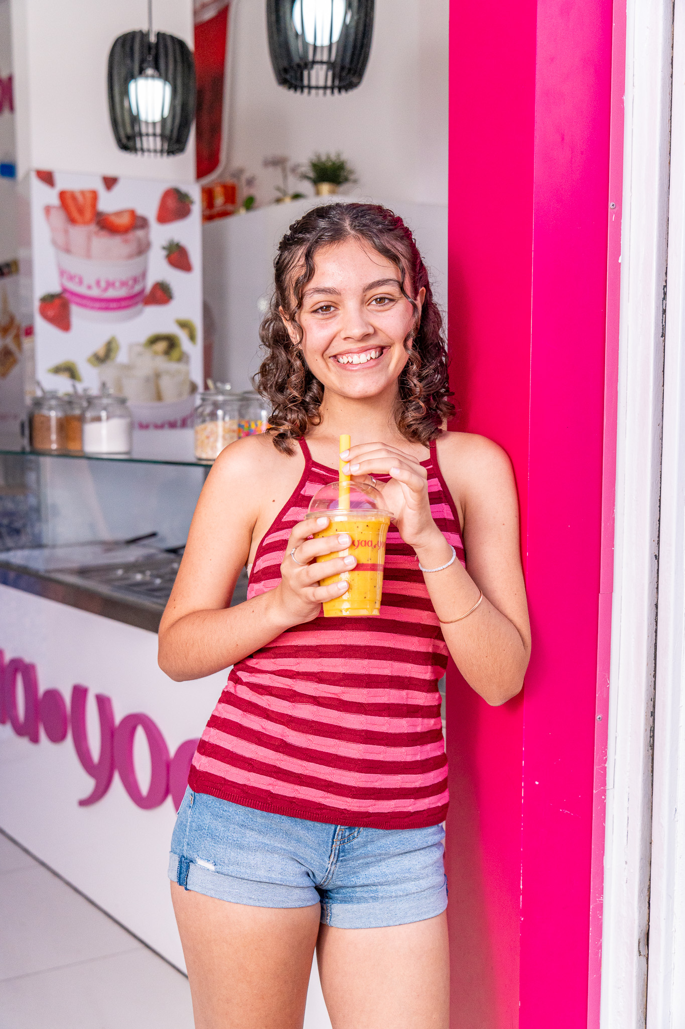 Chica con smoothie de mango frente a Yaa Yogurt