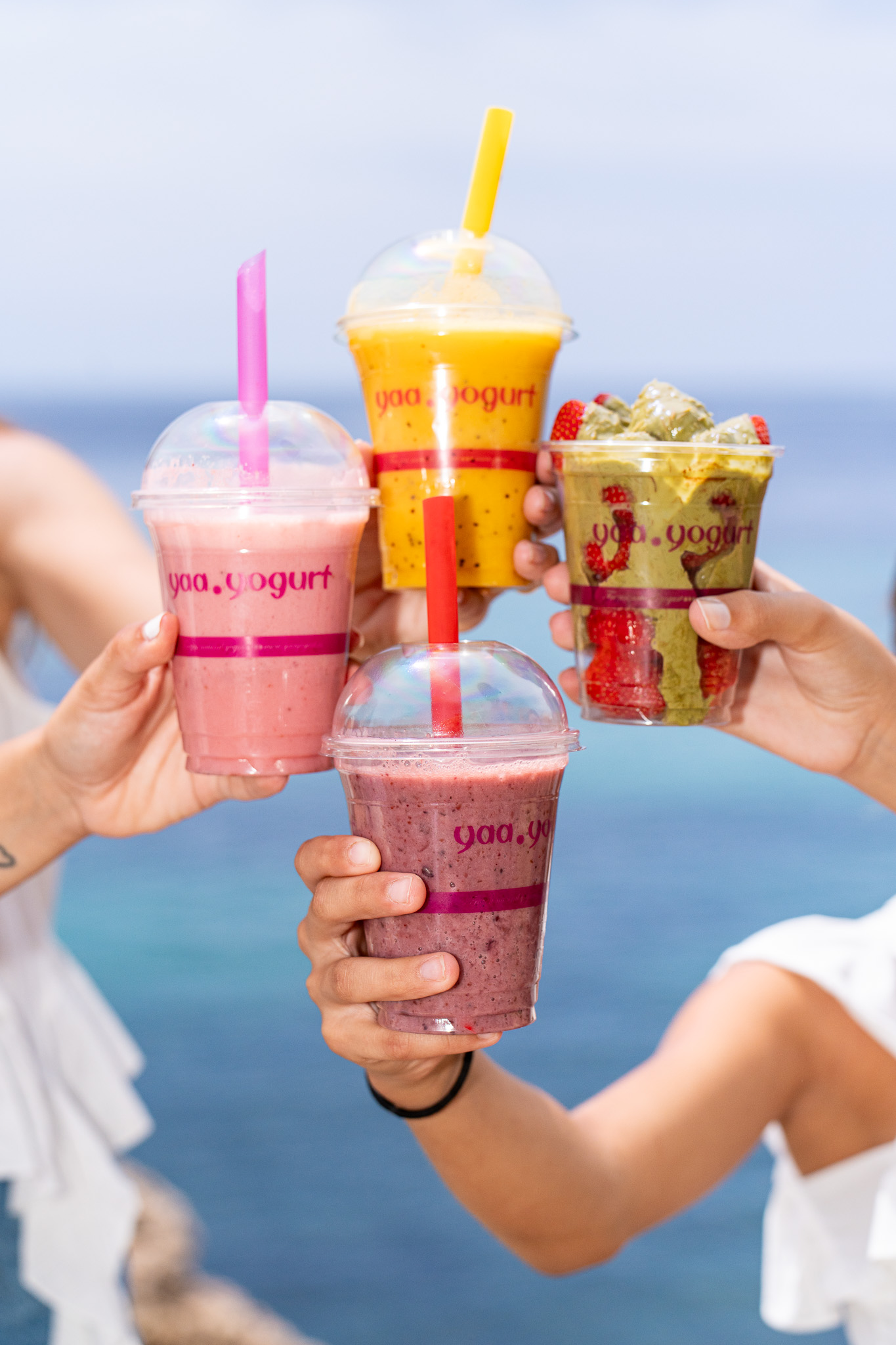 Amigos brindando con smoothies y Yaa Fruit junto al mar